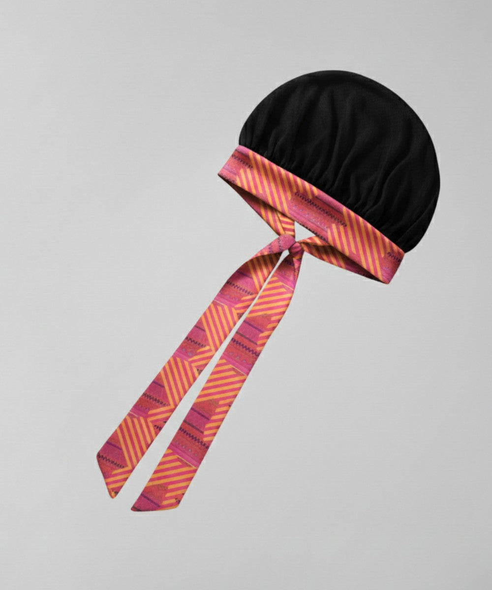 Flat lay of a Lew's Collections satin hair bonnet, featuring a classic black mesh lattice cap and a multicolored 'Aztec Afrique' adjustable satin tie band with a knot.