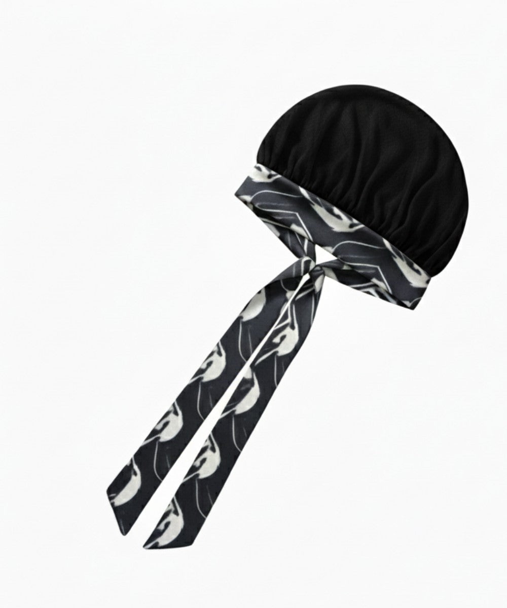 Flat lay of a Lew's Collections satin hair bonnet, featuring a neutral black mesh lattice cap and a multicolored 'Marble Noir' adjustable satin tie band with a knot.