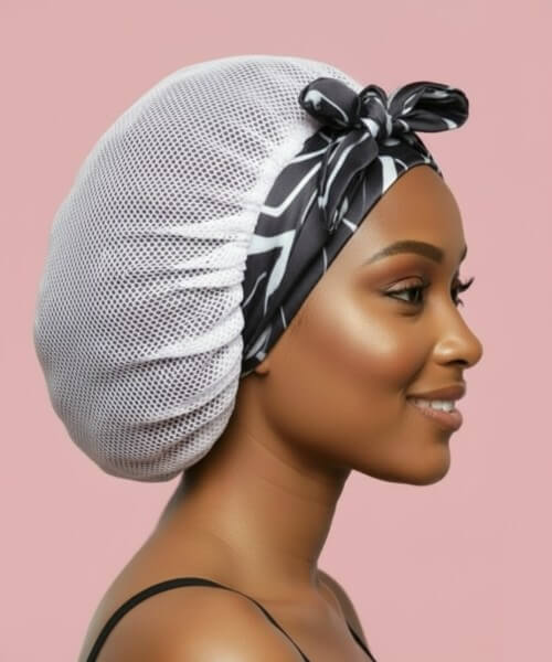 Profile of a smiling woman wearing a white breathable hair bonnet with a tied black and white marble satin band, emphasizing gentle hair and edge care.